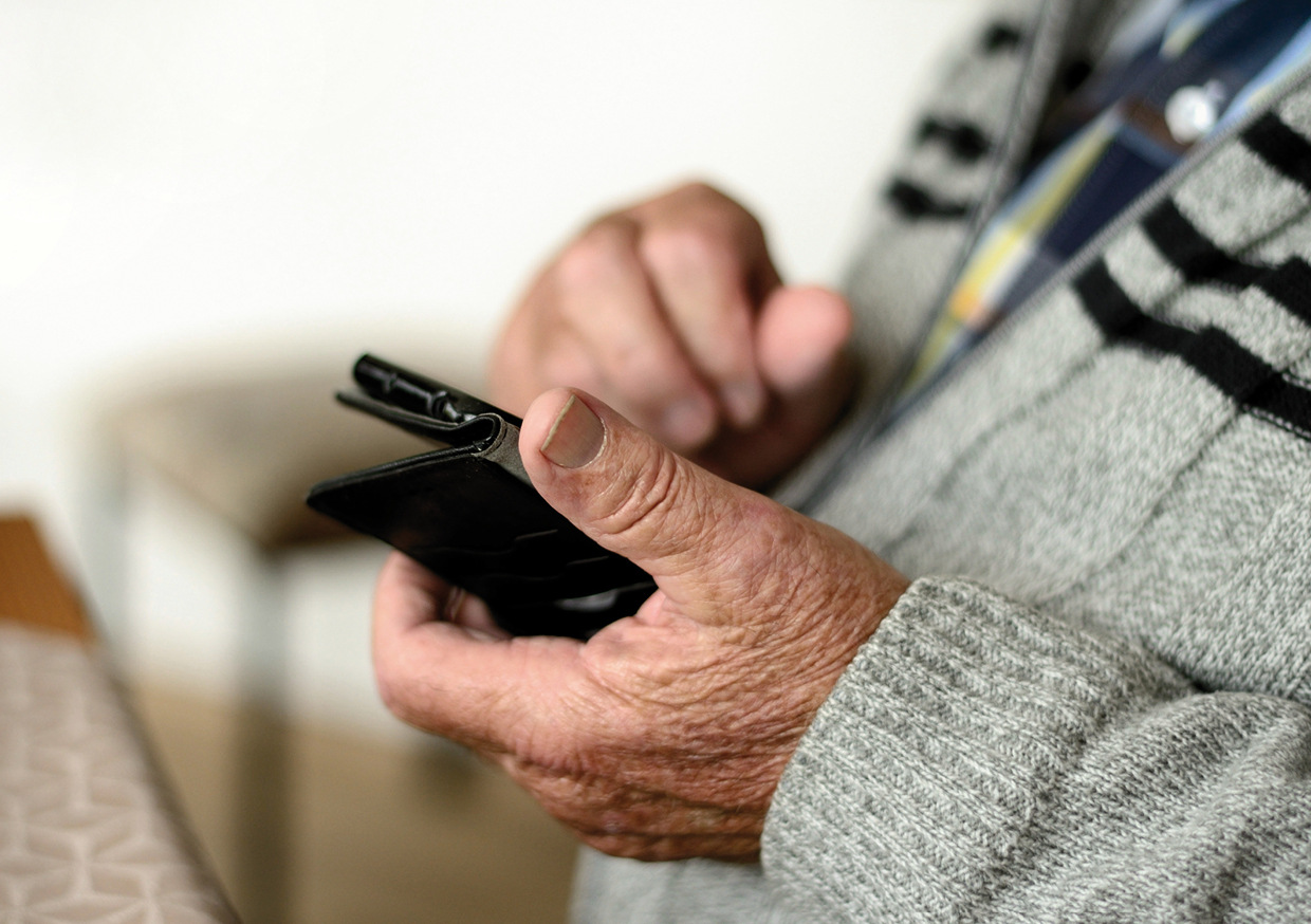 Älterer Mensch mit Handy in der Hand