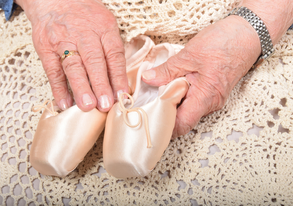 Hände einer älteren Frau halten Ballerina-Schuhe