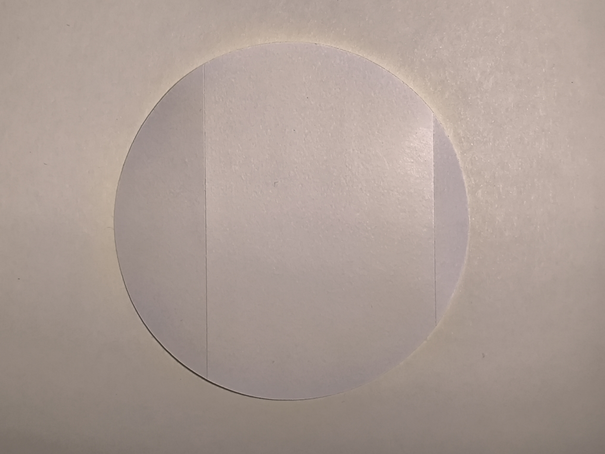 Rückseite eines runden Aufklebers mit sichtbaren Schlitzen zur einfacheren Ablösung